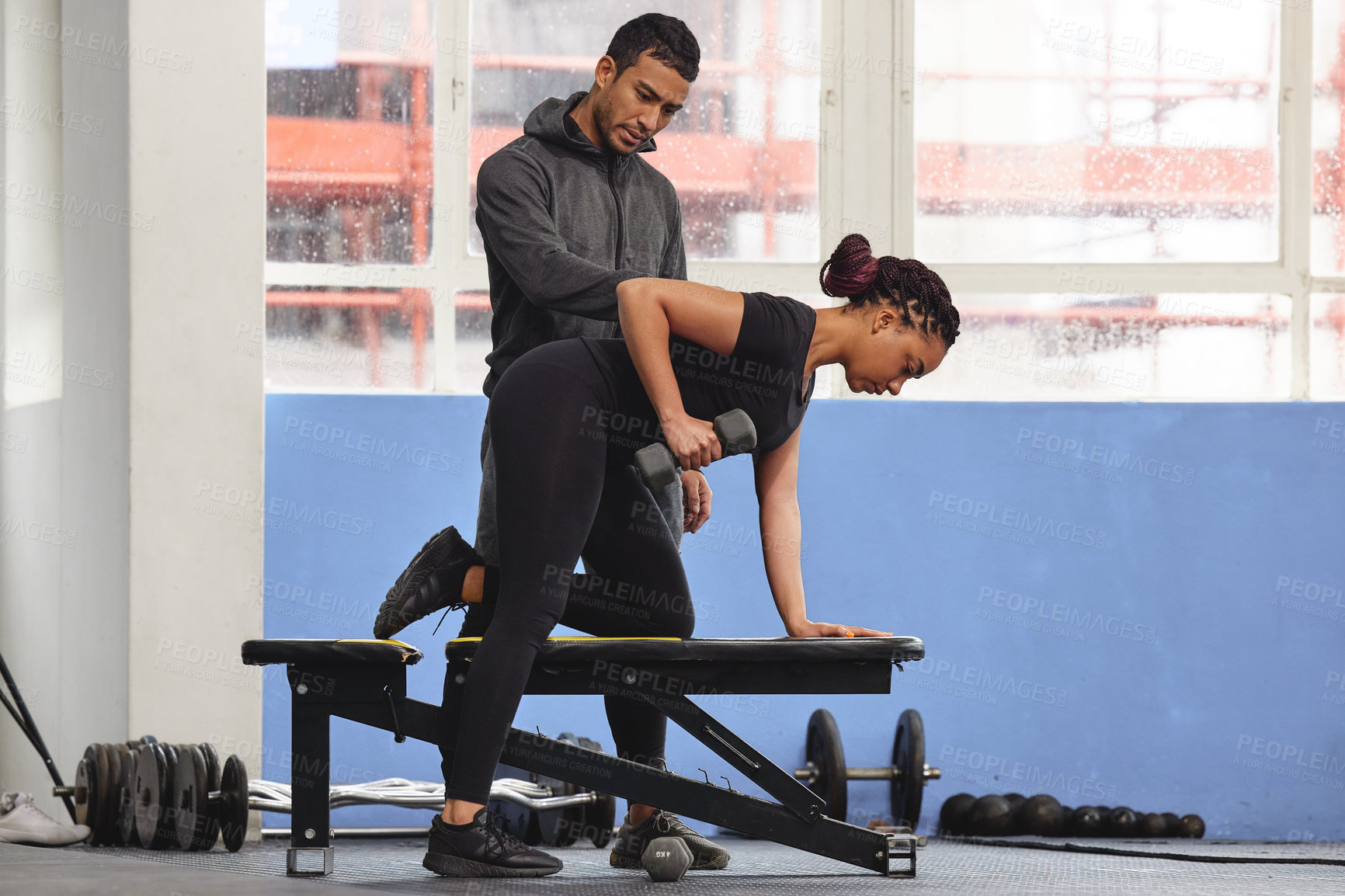 Buy stock photo Shot of a young woman exercising with a trainer at the gym