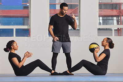 Buy stock photo Shot of two young women exercising with a trainer at the gym