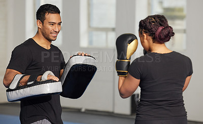 Buy stock photo Shot of a young man training a client in a boxing gym