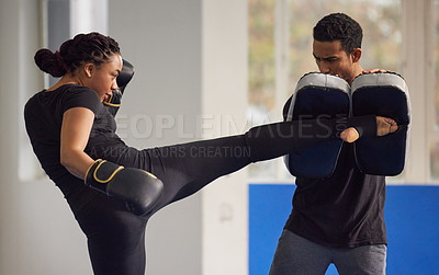 Buy stock photo Shot of a young woman practicing kickboxing with her trainer in a gym