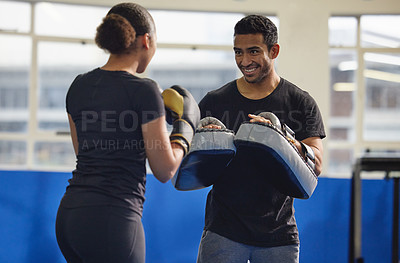 Buy stock photo Shot of a young man training a client in a boxing gym