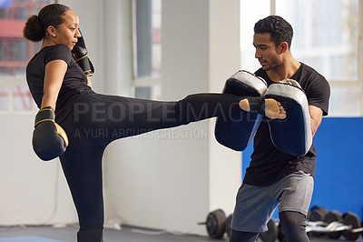 Buy stock photo Shot of a young woman practicing kickboxing with her trainer in a gym