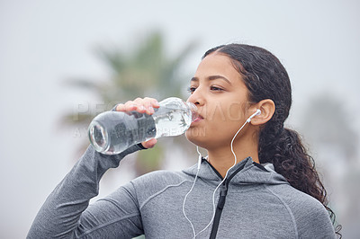 Buy stock photo Shot of a young woman drinking water while exercising in nature