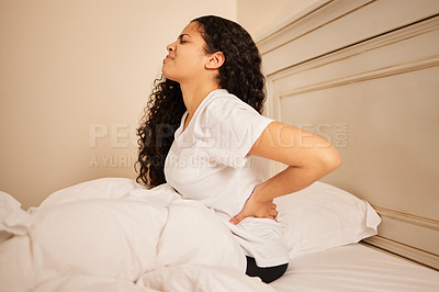 Buy stock photo Shot of a young woman holding her stomach in pain in bed at home