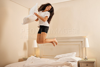 Buy stock photo Shot of a young woman jumping on her bed at home