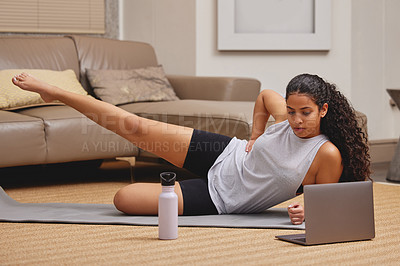 Buy stock photo Full length shot of a young woman using her laptop to follow an online fitness class in her living room
