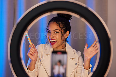 Buy stock photo Shot of a young woman using a phone and ring light to film a makeup tutorial at home