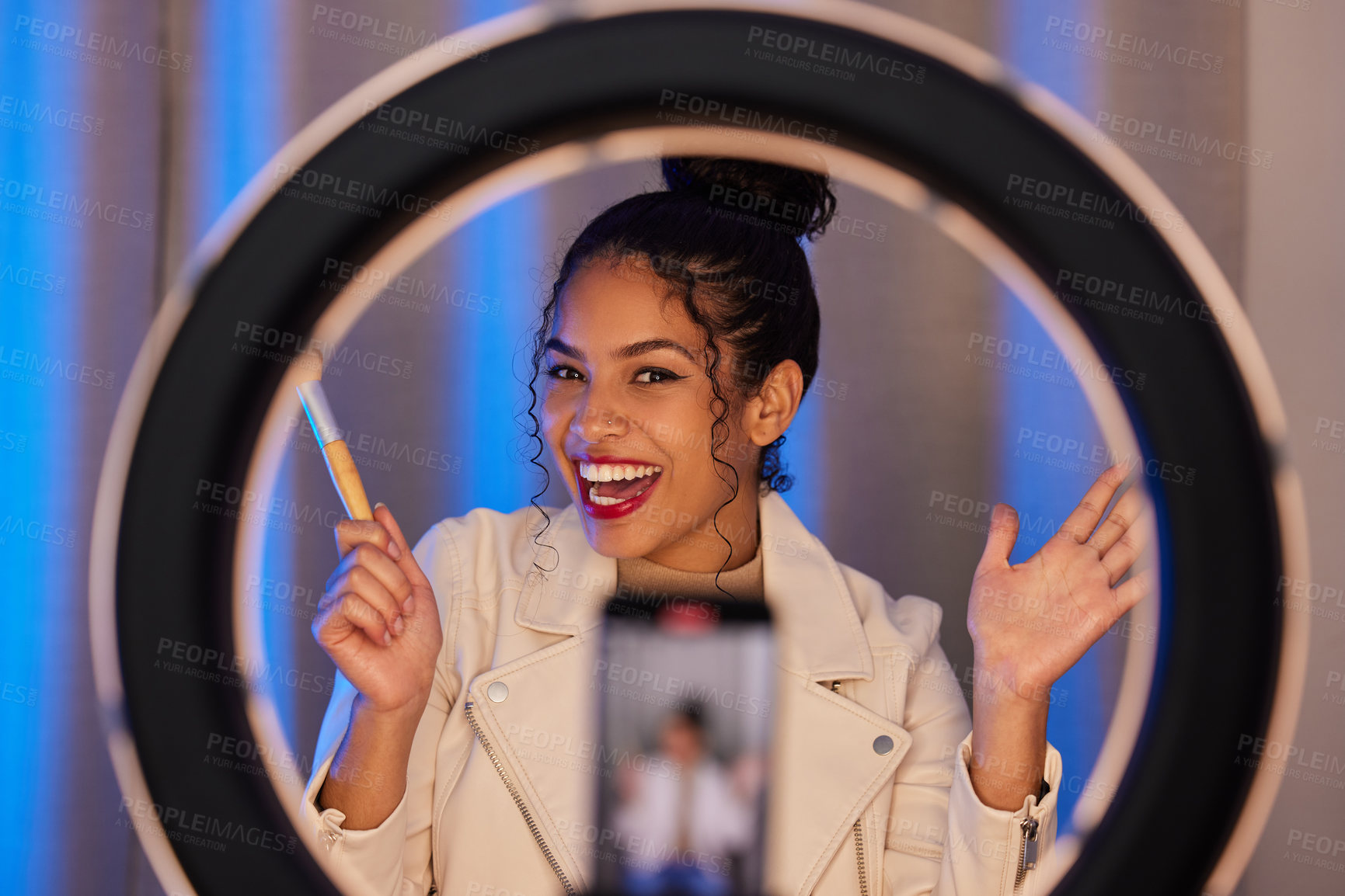 Buy stock photo Shot of a young woman using a phone and ring light to film a makeup tutorial at home