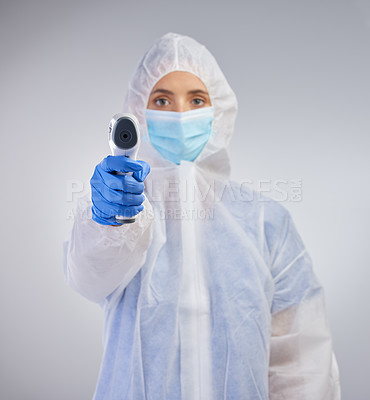 Buy stock photo Shot of a young female nurse holding a digital thermometer against a studio background