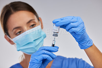 Buy stock photo Shot of a nurse filling up a syringe with vaccination fluid against a studio background