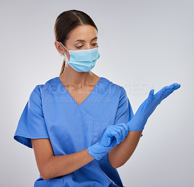 Buy stock photo Shot of a female nurse putting on her protective gloves