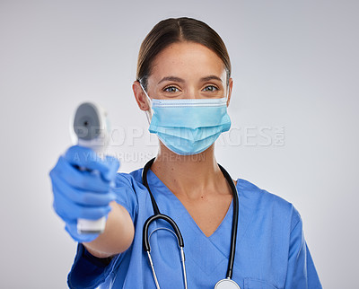 Buy stock photo Shot of a young female nurse holding a digital thermometer against a studio background