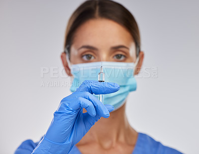 Buy stock photo Shot of a young female nurse holding a needle against a studio background