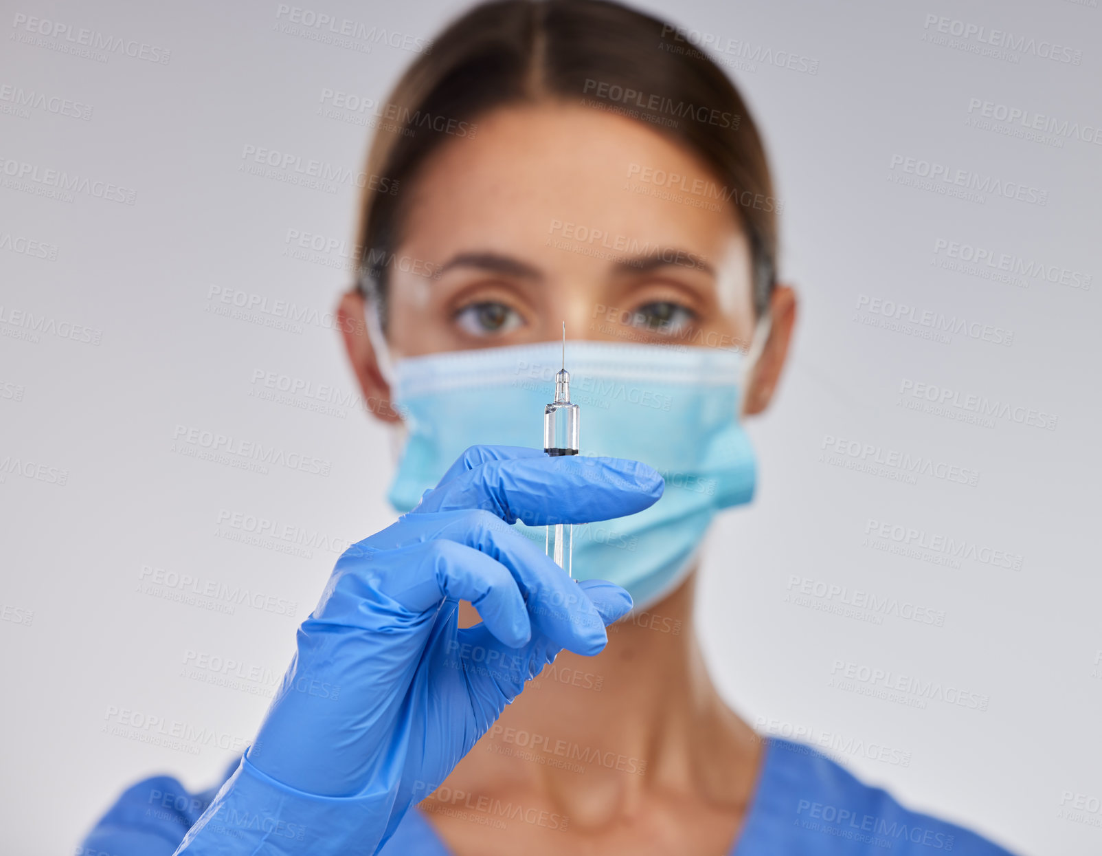 Buy stock photo Shot of a young female nurse holding a needle against a studio background