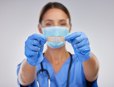 Buy stock photo Shot of a young female nurse holding a plaster against a studio background
