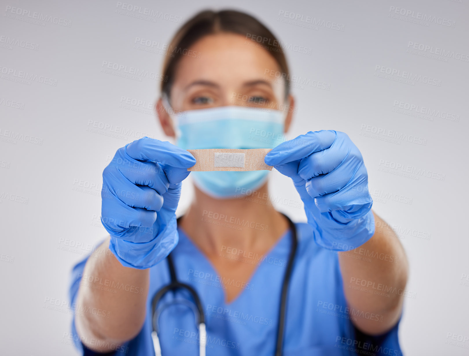 Buy stock photo Shot of a young female nurse holding a plaster against a studio background