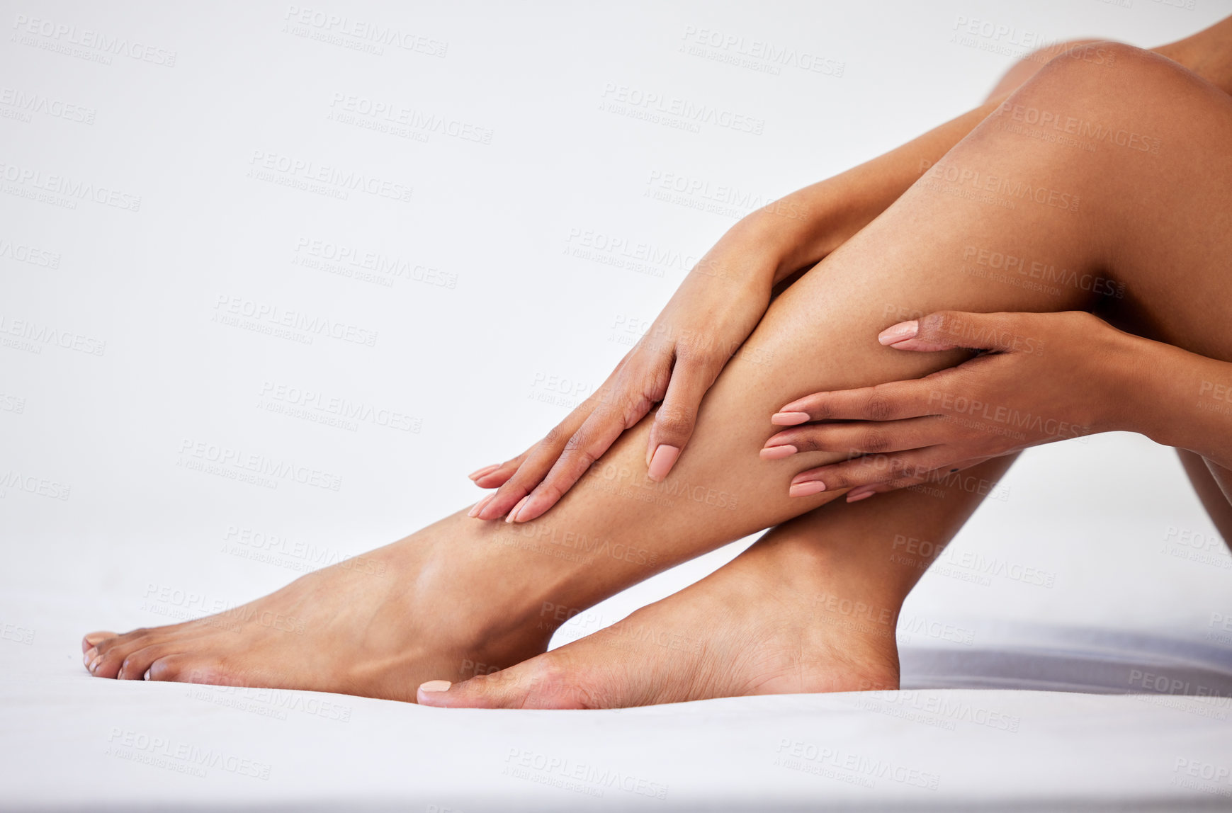 Buy stock photo Cropped shot of an unrecognisable woman touching her legs while sitting against a white background