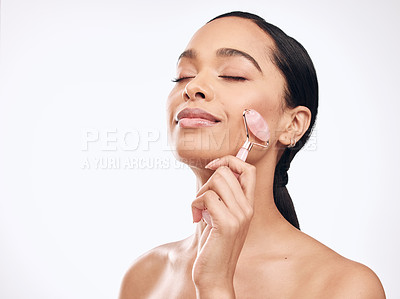 Buy stock photo Studio shot of a young woman holding a derma roller against a white background