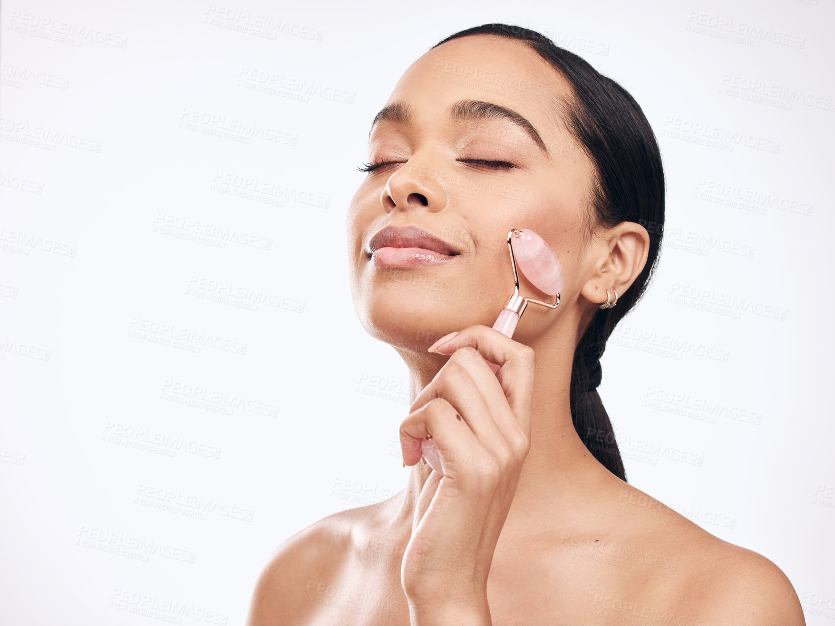 Buy stock photo Studio shot of a young woman holding a derma roller against a white background