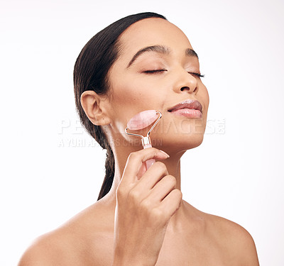 Buy stock photo Studio shot of a young woman holding a derma roller against a white background