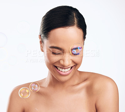 Buy stock photo Shot of bubbles floating over a beautiful woman in the studio