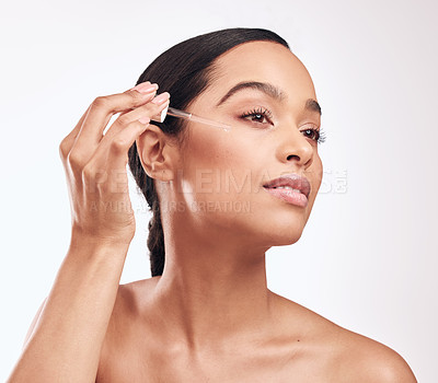 Buy stock photo Shot of a beautiful young woman holding a serum dropper against her face