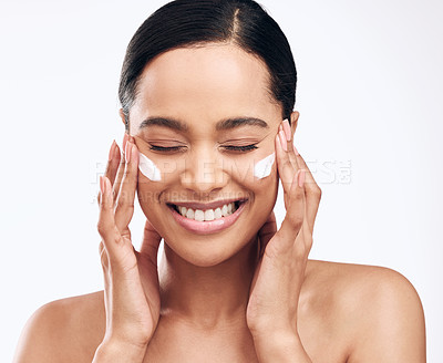 Buy stock photo Studio shot of a beautiful young woman applying moisturiser to her face