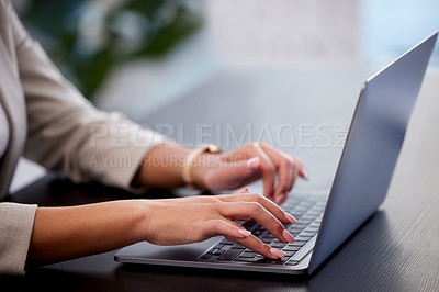 Buy stock photo Cropped shot of a young businesswoman using a laptop at her desk in a modern office