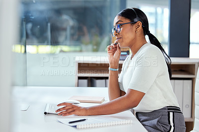 Buy stock photo Shot of an attractive young businesswoman sitting alone in her office and wearing a headset while using her computer