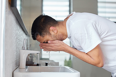 Buy stock photo Shot of a young man washing his face in a bathroom at home