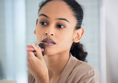 Buy stock photo Shot of an attractive young woman standing alone in her bathroom at home and applying face powder