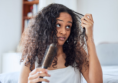 Buy stock photo Shot of an attractive young woman standing alone at home and brushing her curly hair in the morning