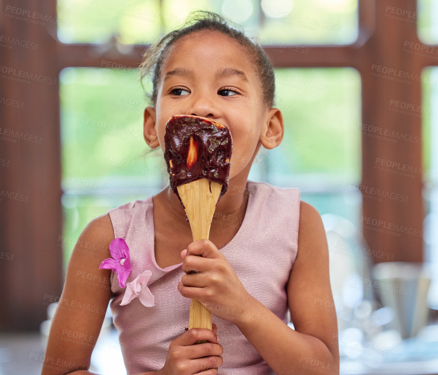 Buy stock photo Shot of an adorable little girl licking a chocolate batter covered spoon while baking in the kitchen at home
