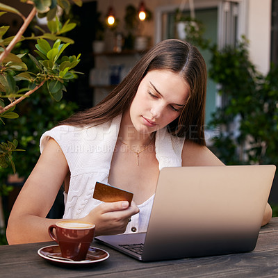 Buy stock photo Shot of a young woman using her debit card to shop on her laptop