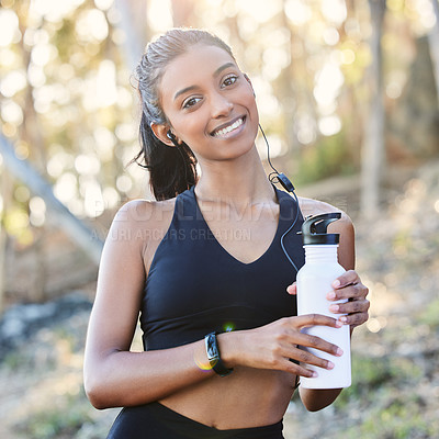 Buy stock photo Fitness, portrait and woman with a bottle in the woods after running for race or marathon training. Sports, earphones and female athlete listening to music for cardio workout with water for hydration