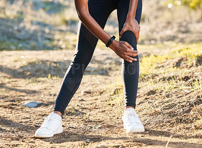 Buy stock photo Shot of a woman experiencing knee pain while working out in nature