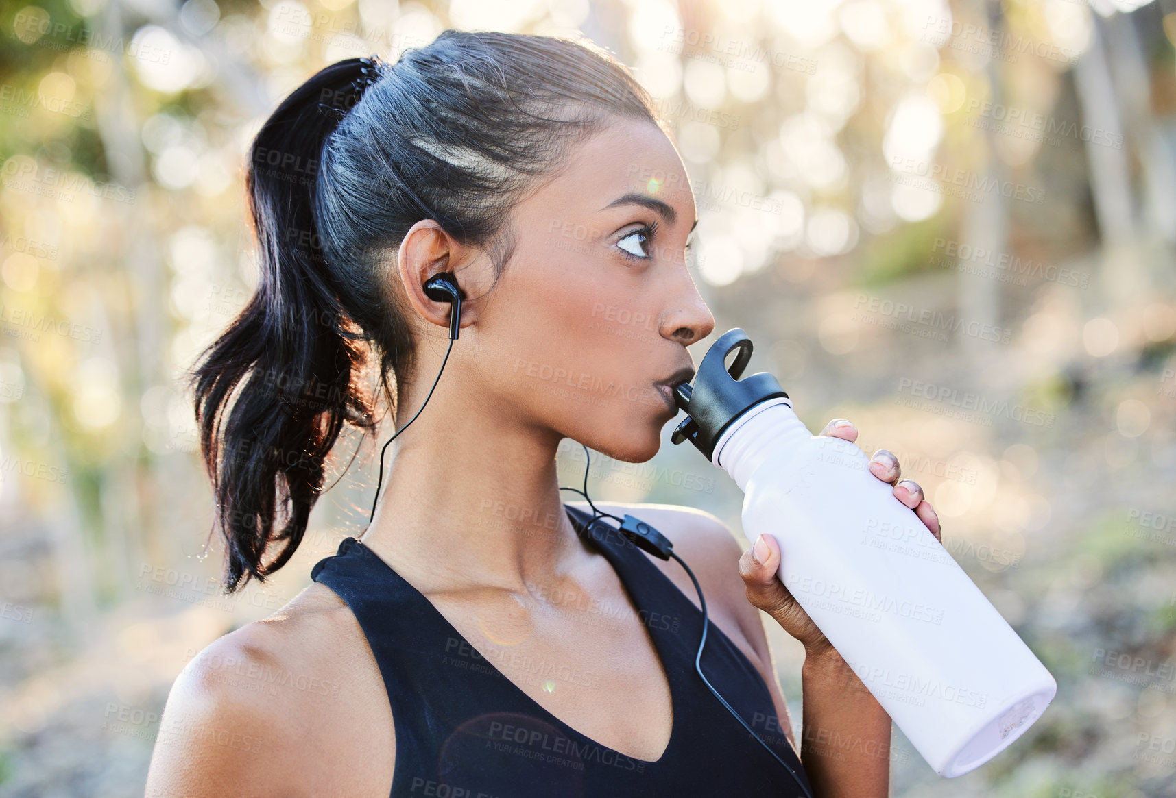 Buy stock photo Shot of a young woman drinking water after working out in nature