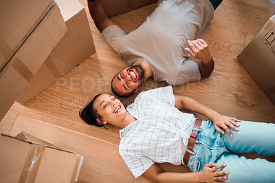 Buy stock photo Shot of a happy couple lying on the floor together in their new home