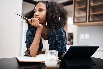 Buy stock photo Shot of a young girl looking unhappy while doing a school assignment at home