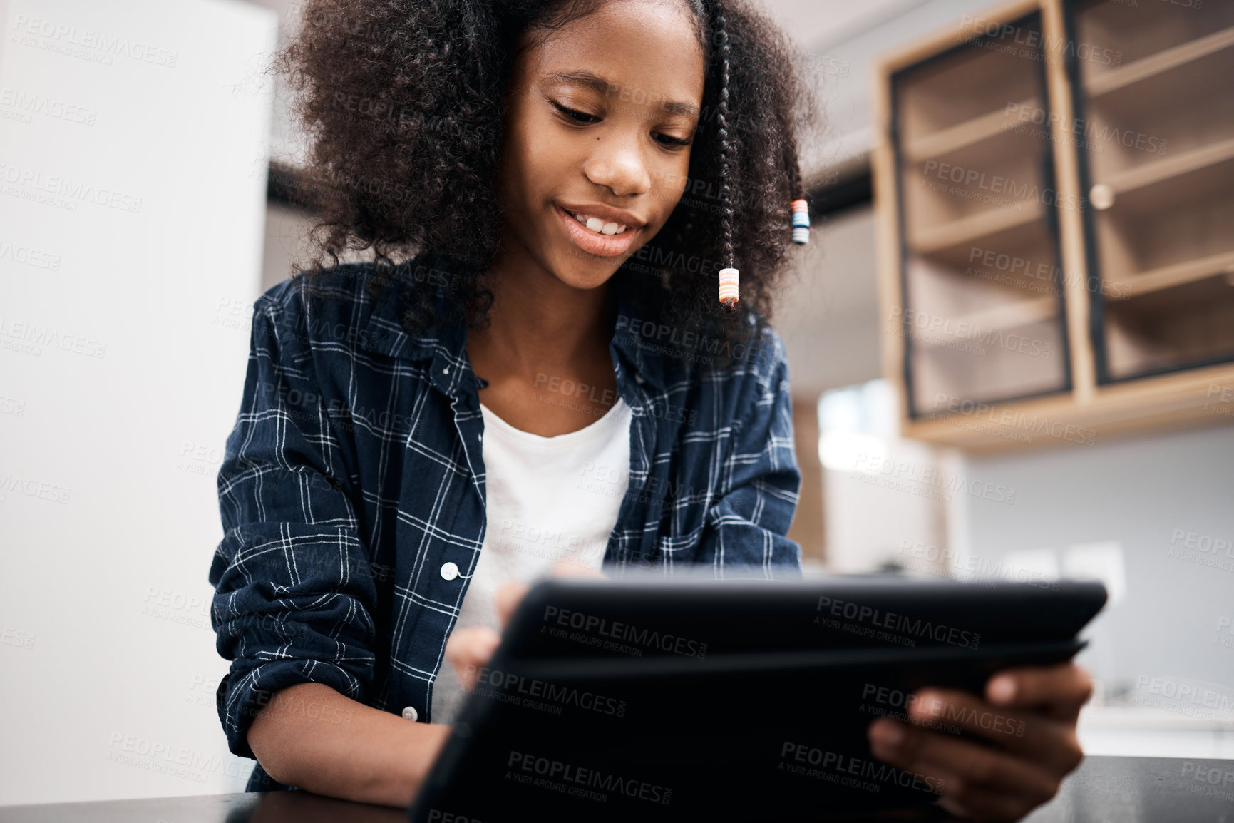 Buy stock photo Shot of a young girl using a digital tablet while doing a school assignment at home