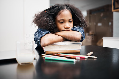 Buy stock photo Shot of a young girl looking unhappy while doing a school assignment at home