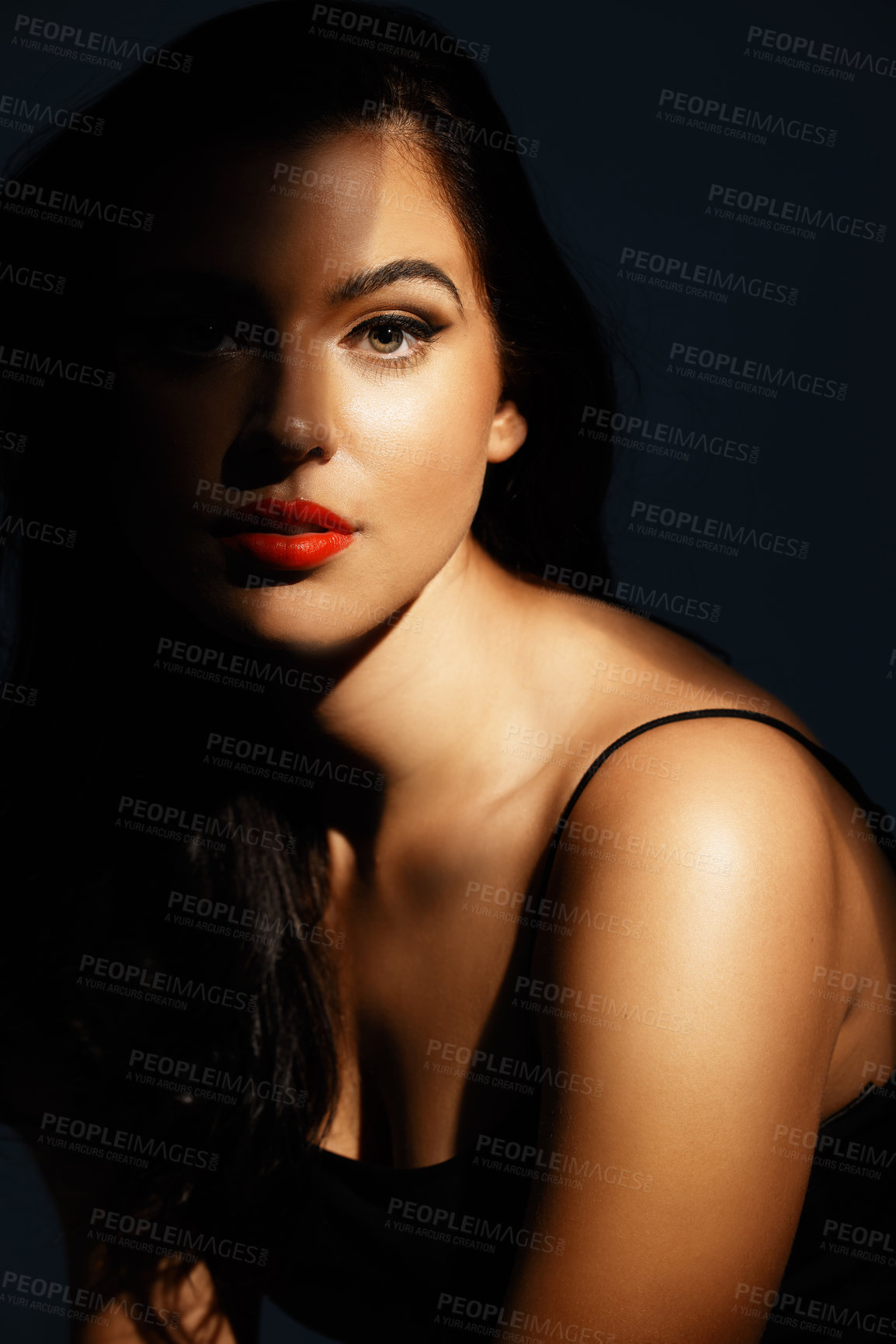 Buy stock photo Studio portrait of an attractive young woman posing against a dark background