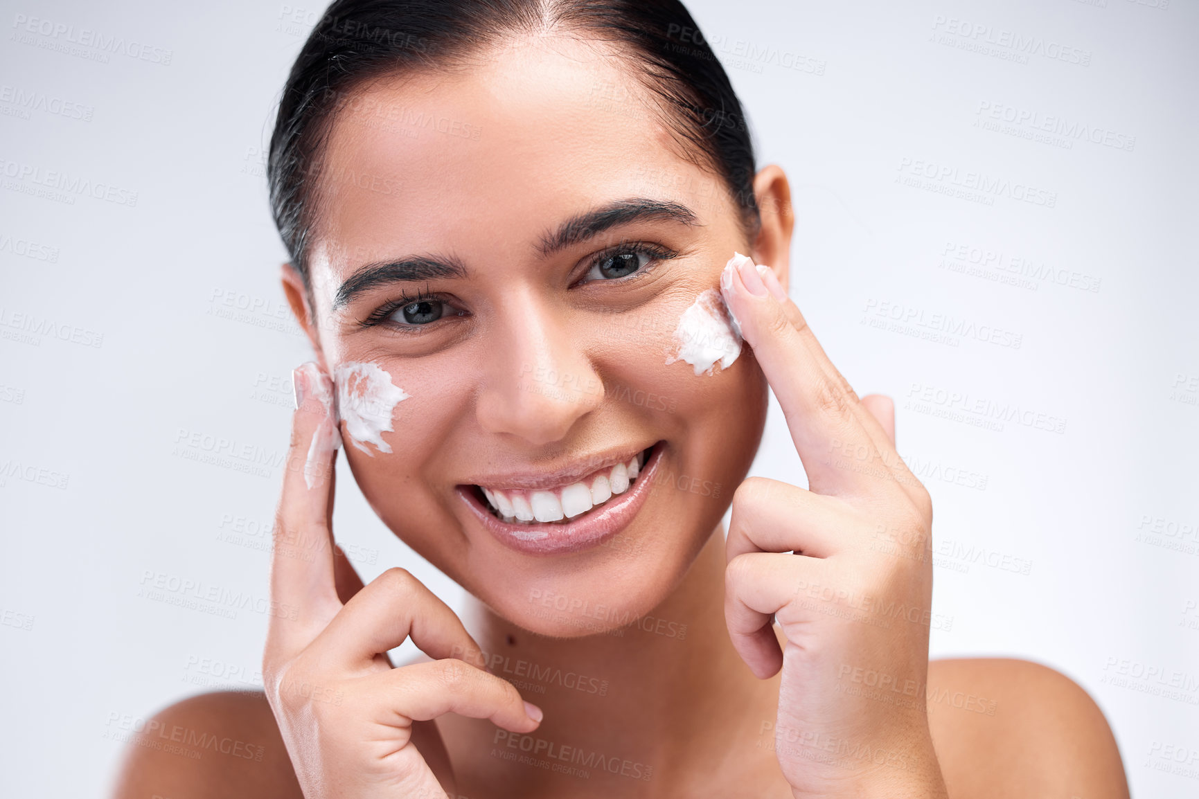 Buy stock photo Shot of a beautiful young woman applying moisturiser to her face