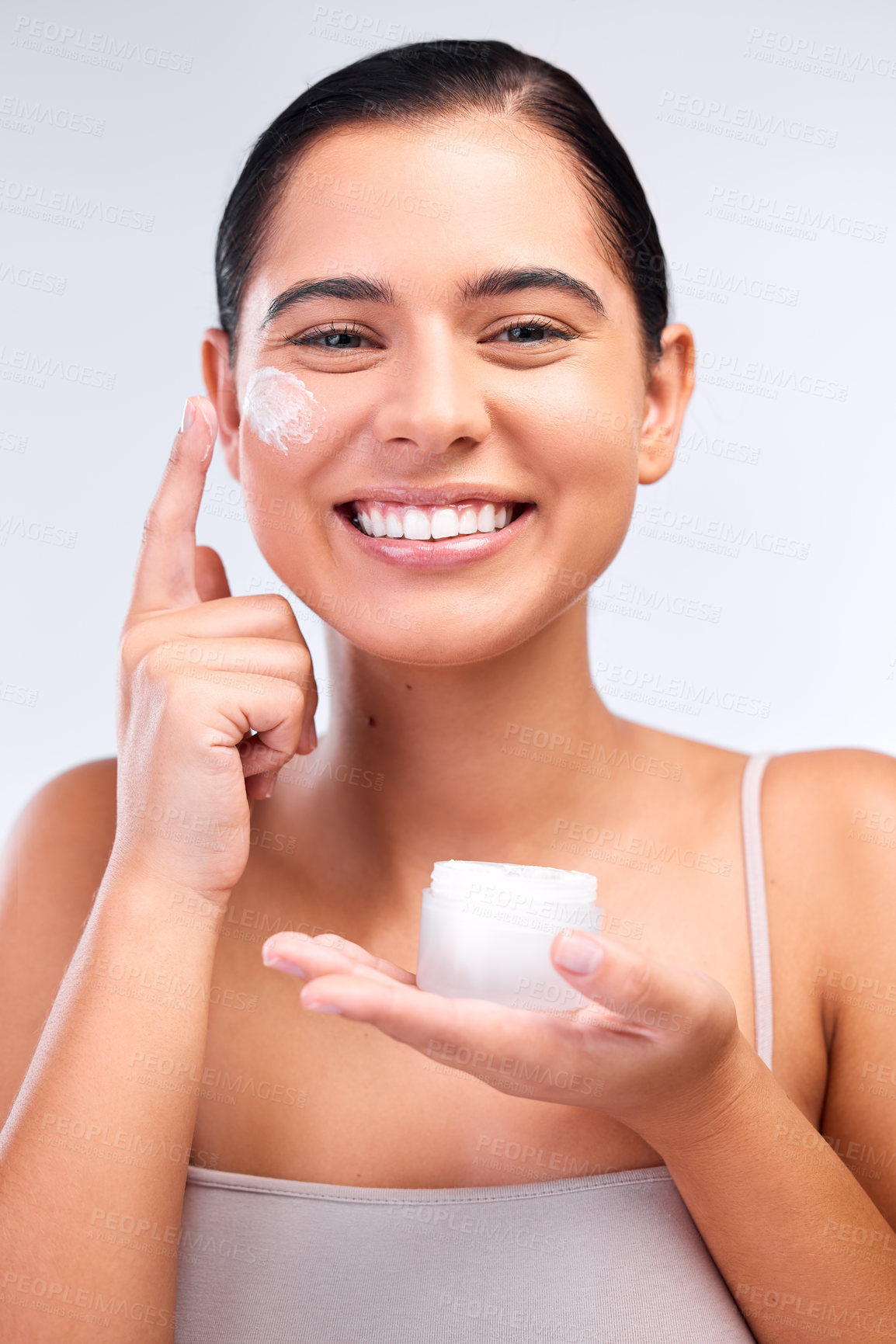 Buy stock photo Shot of a beautiful young woman applying moisturiser to her face