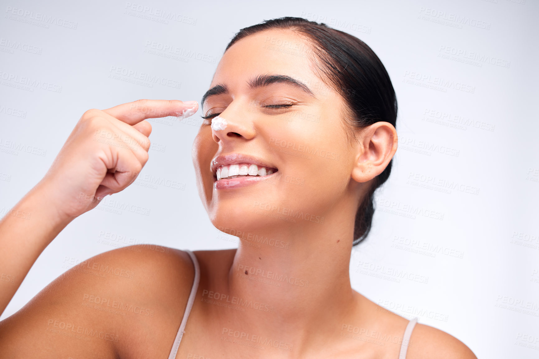 Buy stock photo Shot of a beautiful young woman applying moisturiser to her face