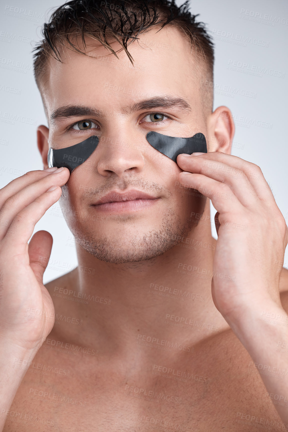 Buy stock photo Closeup portrait of a young handsome man wearing an under-eye charcoal patch against a grey background