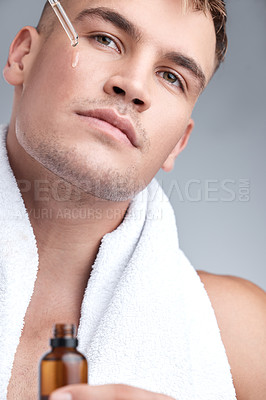 Buy stock photo Skincare, oil and man with serum, dermatology and natural beauty against a grey studio background. Face, male person or model with cosmetics, wellness and spa treatment with grooming routine and glow