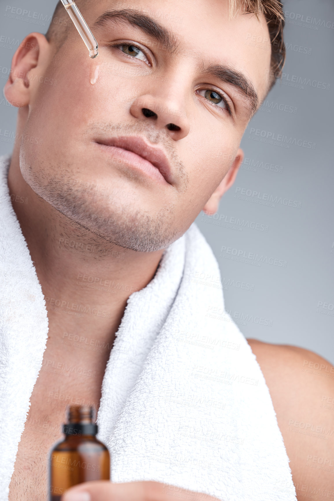 Buy stock photo Skincare, oil and man with serum, dermatology and natural beauty against a grey studio background. Face, male person or model with cosmetics, wellness and spa treatment with grooming routine and glow