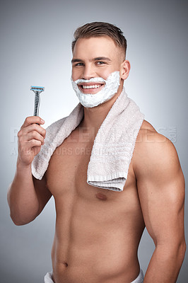 Buy stock photo Studio portrait of an attractive young man shaving his face against a grey background