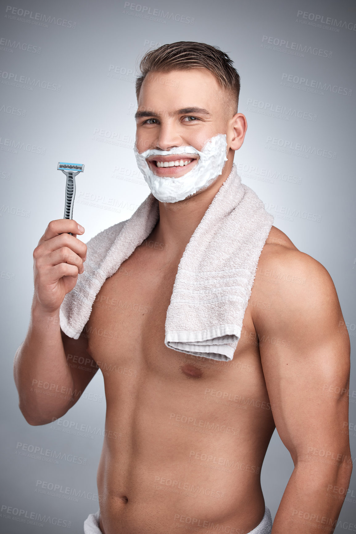 Buy stock photo Studio portrait of an attractive young man shaving his face against a grey background